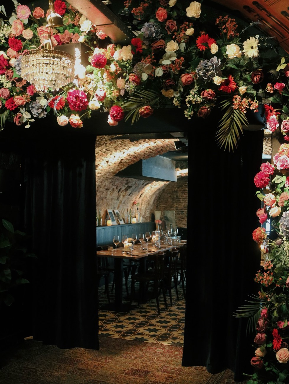 Doorkijk met bloemen naar een lange gedekte tafel in de werfkelder
