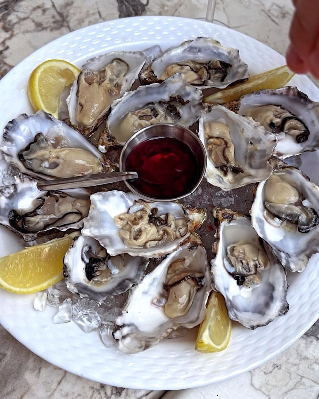 Schaal met twaalf oesters op ijs, met citroen en mignonette