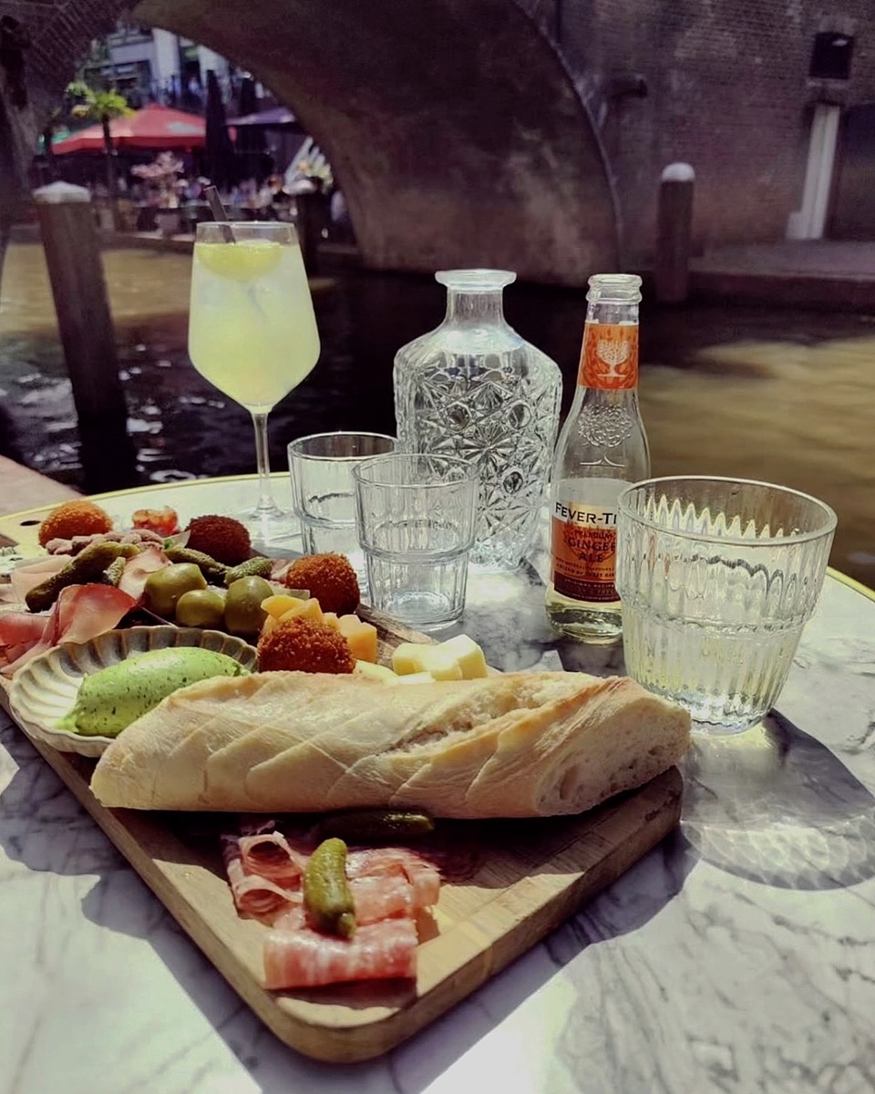 Lunchgerechten en bloemen op een terrastafel aan het water